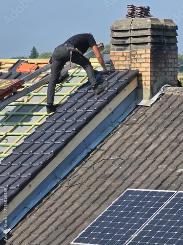Ouvrier qui rénove la toiture d’une maison pour isolation et remplacement des tuiles
