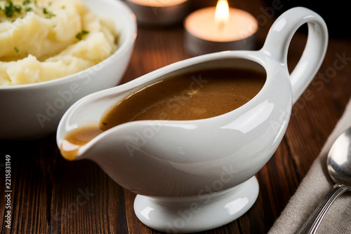 White porcelain gravy boat with brown gravy and mashed potatoes