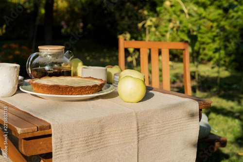 Homemade apple pie and hot tea on cozy wooden garden table