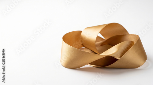 Golden ribbon tied into an abstract knotted shape on white