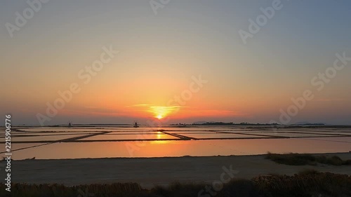 Golden sunset over tranquil salt pans near Trapani, Italy
