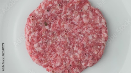 Raw pork meat cutlet spinning on plate