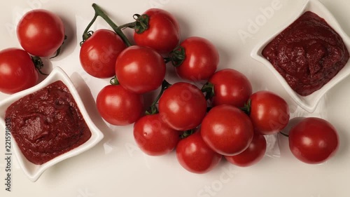 Fresh cherry tomatoes and sauce on white background