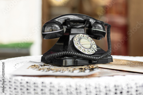 intage black rotary telephone on a table outdoors close up.