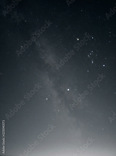 Night sky filled with stars and a hazy band of the Milky Way above in soft daylight