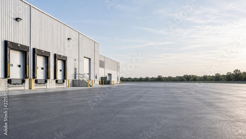 Modern Metal Warehouse with Loading Bays beside an Empty Asphalt Yard