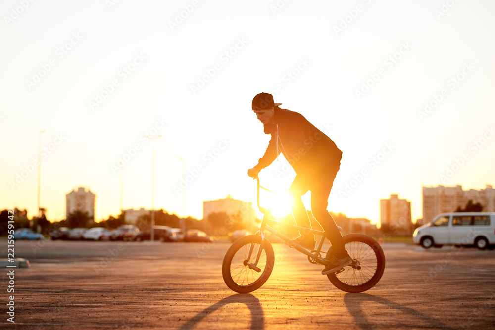 Naklejka premium BMX, flare and ride with man on bike in city for activity, adrenaline hobby or sports training. Exercise, balance and risk with extreme person on bicycle on street for action, cycling or energy