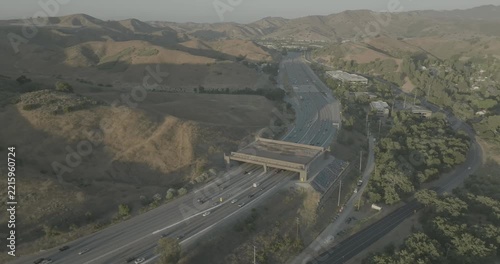 Drone shot over busy highway and overpass in backlit hazy hills