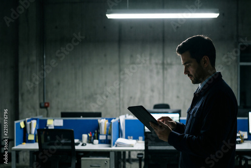 Businessman using a tablet in an industrial office at night