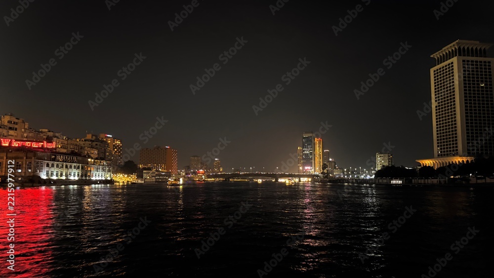 Fototapeta premium Night view of the Nile river reflecting city lights and illuminated skyscrapers of downtown Cairo