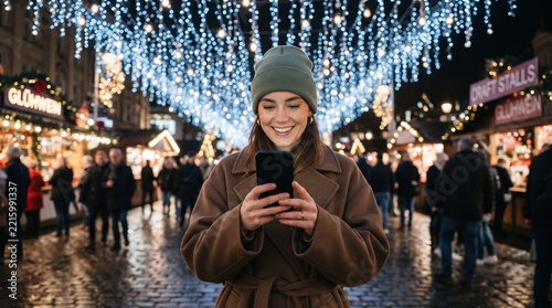 Young woman using a smartphone outside with the decorative christmas lights in the background