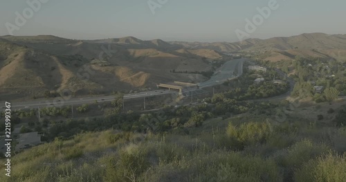 Drone shot of freeway curving through dry hills and shrubs