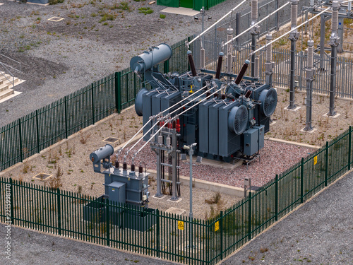 Aerial view of the Clay Tye Tesla Megapack installation featuring large electrical transformers and cooling fans within a fenced substation area in Upminster, England, United Kingdom.