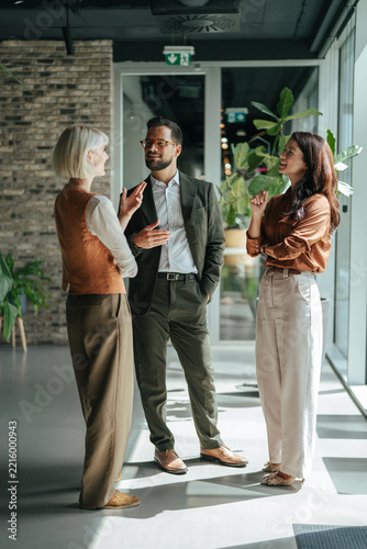 Business colleagues communicating in modern office hallway