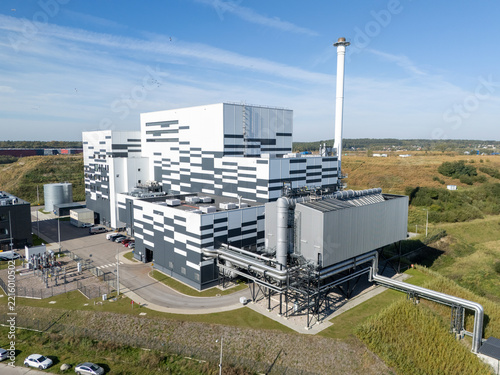 Aerial view of a modern waste incineration plant with a distinctive geometric facade, tall chimney, and industrial piping in Gdansk, Poland.