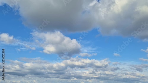 Timelapse video showing white fluffy cumulus clouds rapidly moving across a bright blue sky on a clear sunny day, creating dynamic natural atmospheric movement and peaceful outdoor scenery