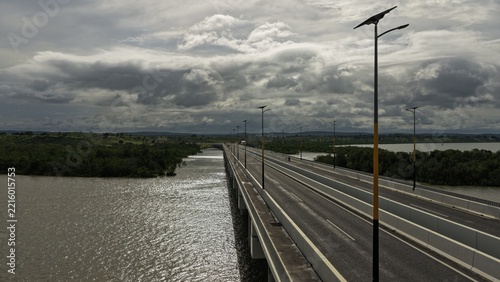 Aerial view of Dongo Kundu Bypass bridge spanning over water with lush mangroves, modern street lighting, and a cloudy sky in Mombasa, Wilaya ya Mombasa, Kenya.