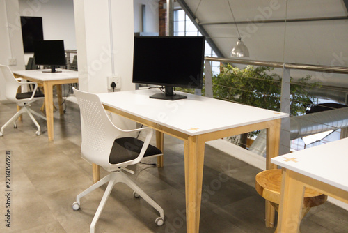 Nearest workstation is sitting on mezzanine with white desk, black monitor, white chair