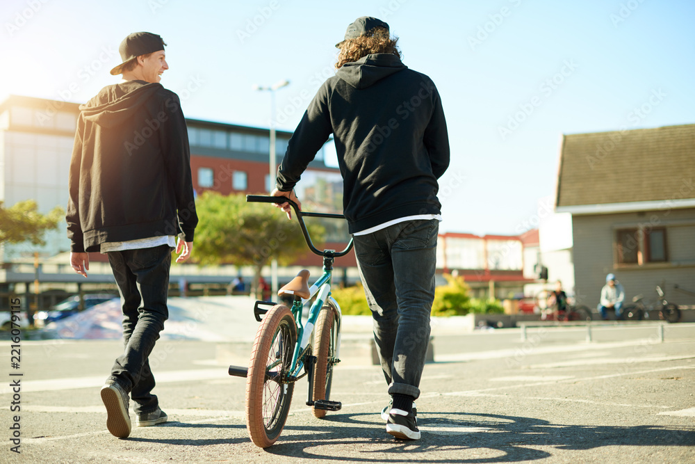 Naklejka premium Friends, back and bicycle for outdoor hobby, activity or challenge in skate park. Bike, people and urban sport for cycling, BMX training and skills for competition with balance and stunt exercise