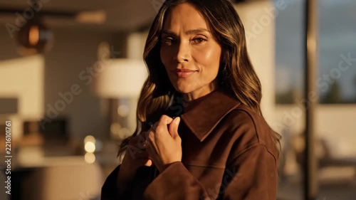 Elegant Woman Adjusting Brown Jacket with Warm Sunset Light, Confident Portrait