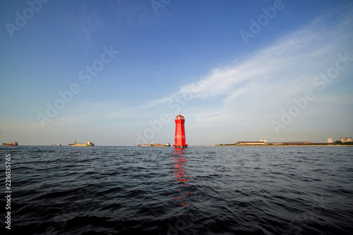  A striking red lighthouse that is no longer in operation remains standing near a harbor, serving as a distinctive maritime landmark in the coastal area.