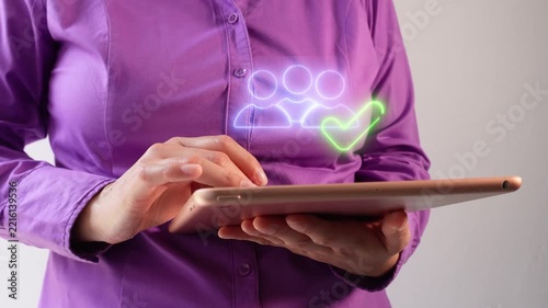 Person uses tablet with holographic people and checkmark