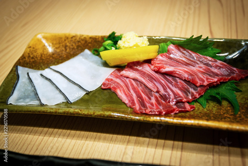 Closeup of kujira sashimi, or raw whale sushi featuring dark red akami whale meat taken from muscle tissue, and translucent white skin blubber shirokawa with a dark edge. It's a rare delicacy in Japan