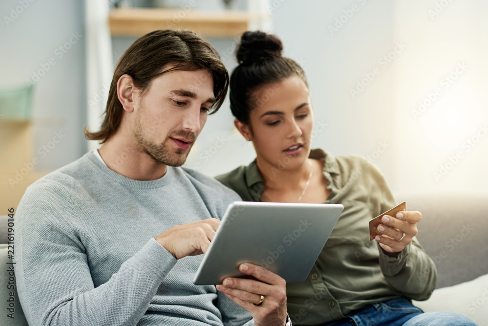 Fototapeta premium Credit card, ecommerce and tablet with couple on sofa in living room of home together. App, checkout payment and online shopping with people in apartment for buying, finance decision or purchase