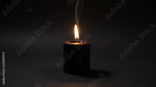 Burning Black Candle with Rising Smoke on Dark Background