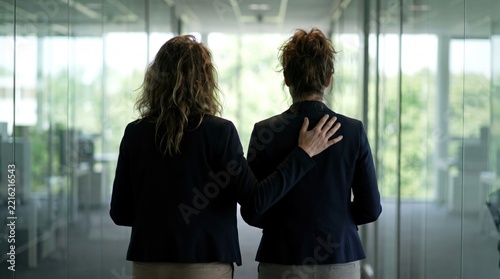 intelligence leader meeting emotional concept. Two women in business attire walking together in an office corridor.