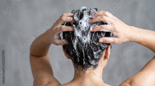 Person massaging shampoo into wet hair with foamy lather. Hair washing and scalp cleansing routine. Personal hygiene and everyday self care. Haircare, beauty and grooming