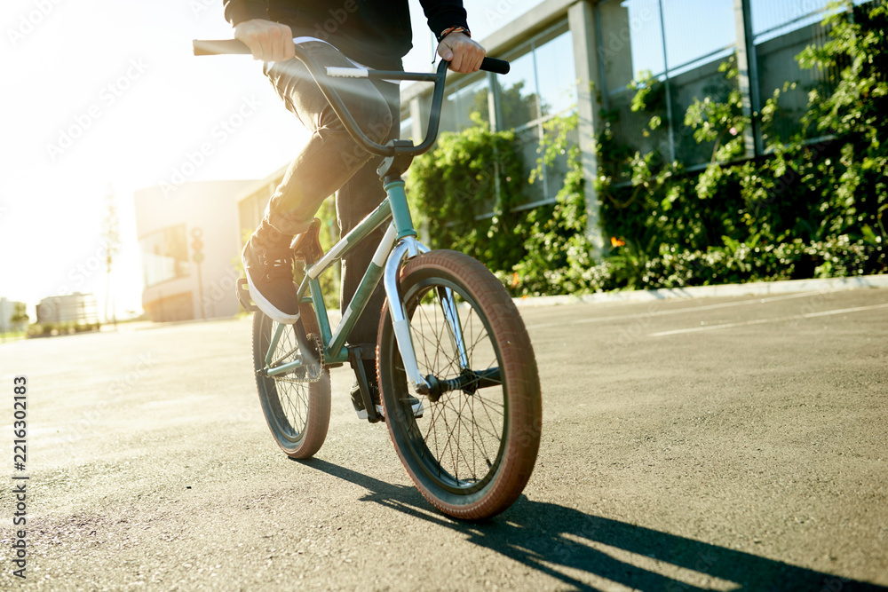 Naklejka premium BMX, legs and bicycle in city for exercise, eco friendly travel and cycling with hands. Person, riding bike and cyclist on road outdoor for fitness, sports and balance on urban street with flare