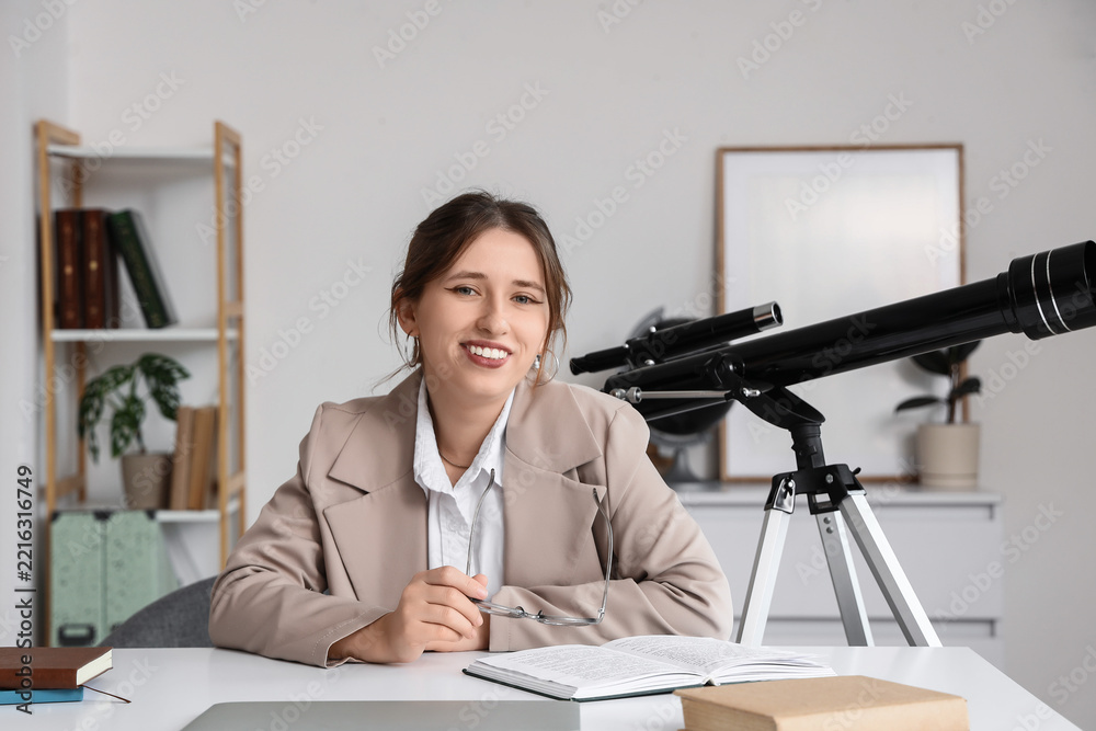 Fototapeta premium Education and scientific research, young woman studying astronomy with a telescope at a desk in a home office environment for academic learning