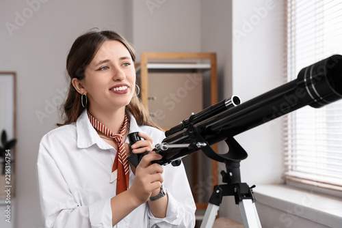 Future vision and career planning, young woman looking through a telescope fo...