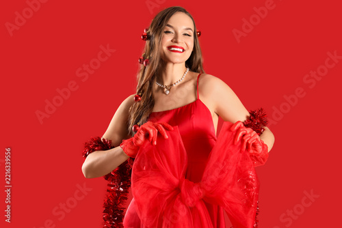 Beautiful young happy woman with Christmas balls in her hair and big bow on r...