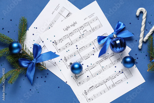 Composition with music sheets, fir branches and Christmas decorations on blue...