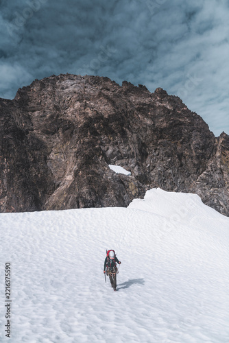 Mountaineer Ascending Snowy Slope Below Rocky Peak