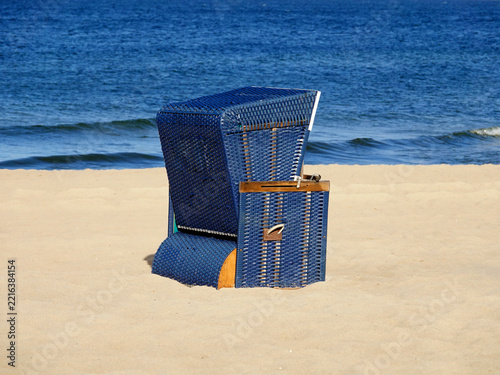 Solitary blue beach basket, beach chair, on a yellow sandy beach next to blue sea
