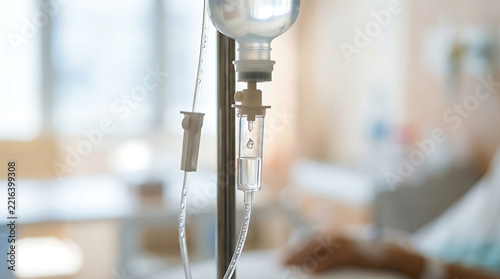 Close-up of intravenous IV drip bag and chamber with saline solution in a bright hospital room.