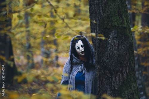 Horror background of a ghostly figure in enchanted a forest on a moody autumn day.