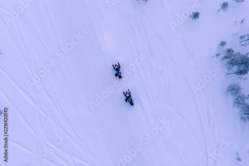 Aerial view of frozen lake and snowmobiles in Finland, Lapland during winter sunset