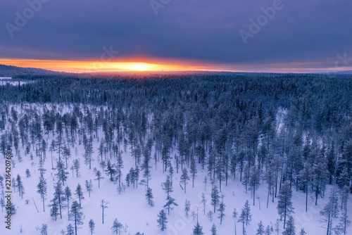 Aerial view of frozen lake and snowmobiles in Finland, Lapland during winter sunset