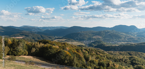 Panoramic view of Dobšiná town in a valley surrounded by forested hills with early autumn colors from Dobšinský kopec viewpoint, Slovak Ore Mountains, Slovakia
