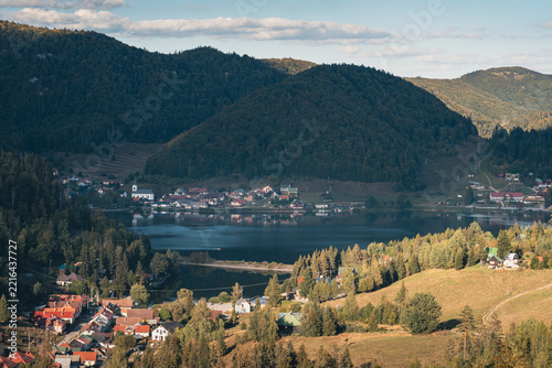 Dedinky village on the shore of Palcmanská Maša reservoir with church, red roofs and forested hills in warm evening light, Slovak Paradise, Slovakia