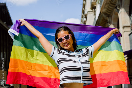 Young woman smiling celebrating lgbtq+ pride with rainbow flag