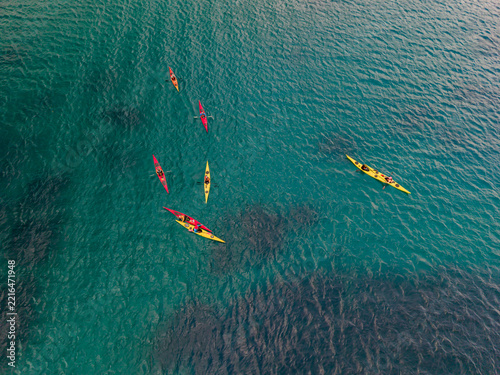 Aerial view of a group of colorful kayaks paddling in the clear turquoise waters of the Mediterranean Sea near the coast of Portoferraio, Tuscany, Italy.