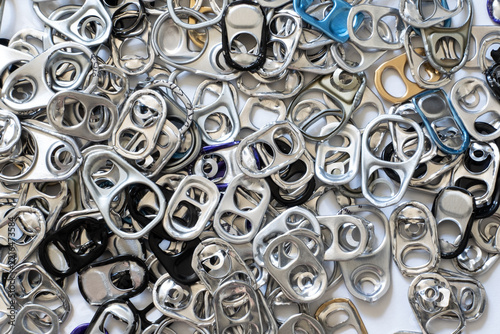 Fotografie Numerous metal pull tabs from beverage cans symbolizing waste, reuse and recycli