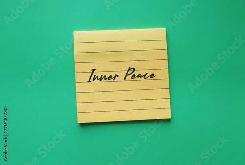 Paper on green background with text written Inner Peace - steady state of psychological and spiritual calm that remains stable even when you face stress, anxiety, or external challenges.