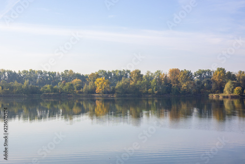 Autumn forest reflected on calm lake water background with copy space