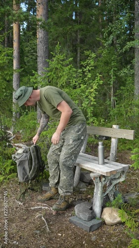 Hiker sitting down to rest on a wooden bench in a forest